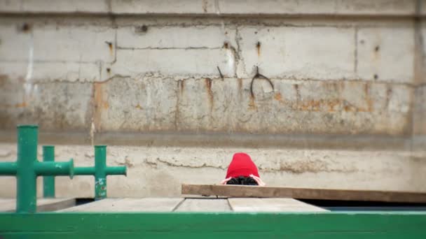 Una hermosa mujer con una chaqueta y un sombrero rojo está de pie en el muelle y mirando a través de binocular — Vídeo de stock