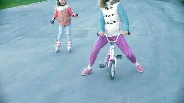 Mãe e filha andam de patins. Menina aprendendo a patinar, e cai. Mãe ensina filha a montar em rolos — Vídeo de Stock