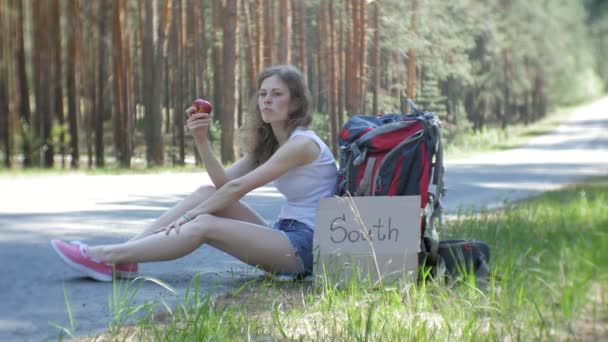 Mladá krásná žena stopování stojící na cestě s batohem na zádech na stole s nápisem jih — Stock video