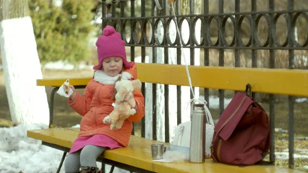 Bella ragazza si siede su una panchina del parco e mangia un delizioso dessert — Foto Stock