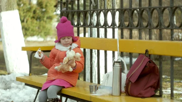 Bella ragazza si siede su una panchina del parco e mangia un delizioso dessert — Foto Stock