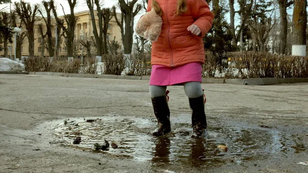 Pequena menina bonita pulando em poças após a chuva — Fotografia de Stock