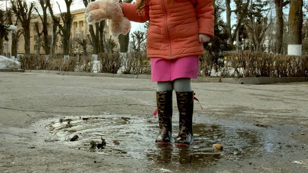 Küçük güzel kız su birikintileri üzerinde yağmur sonrası atlama — Stok fotoğraf