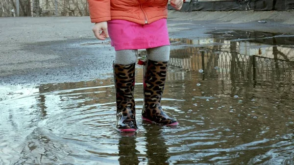 Piccola bella ragazza che salta sulle pozzanghere dopo la pioggia — Foto Stock