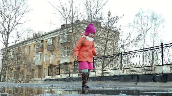 Lilla vackra flicka hoppa på vattenpölar efter regn — Stockfoto
