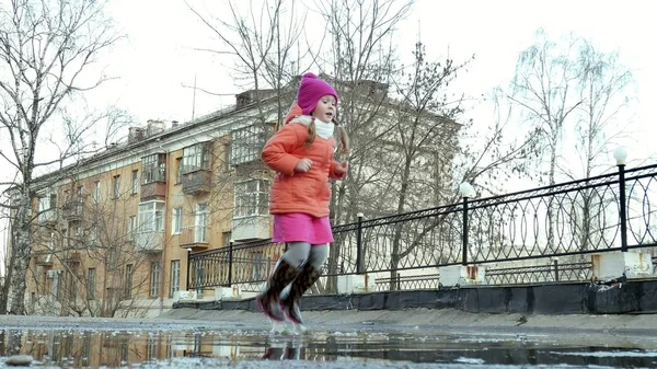 Pequena menina bonita pulando em poças após a chuva — Fotografia de Stock