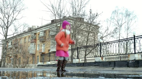 Pequena menina bonita pulando em poças após a chuva — Fotografia de Stock