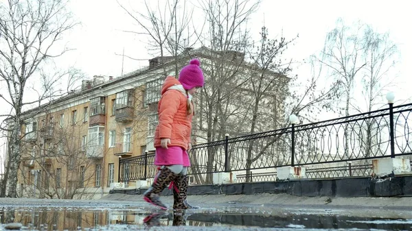 Lilla vackra flicka hoppa på vattenpölar efter regn — Stockfoto