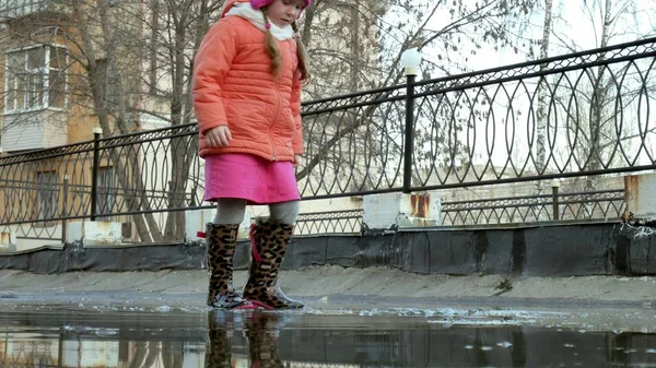 Маленька красива дівчинка стрибає на калюжах після дощу — стокове фото