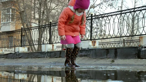 Malá krásná dívka skákání v kalužích po dešti — Stock fotografie