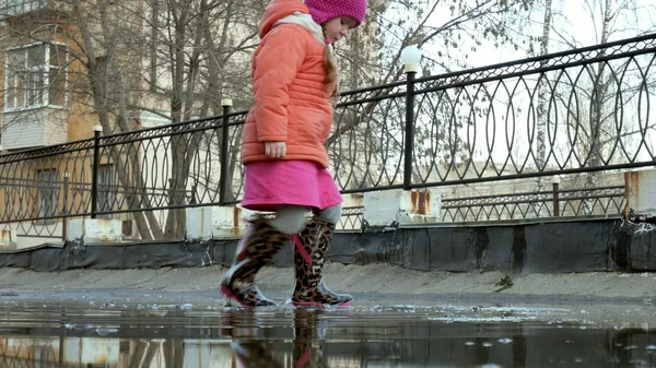 Lilla vackra flicka hoppa på vattenpölar efter regn — Stockfoto