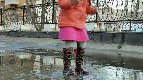 Lilla vackra flicka hoppa på vattenpölar efter regn — Stockfoto