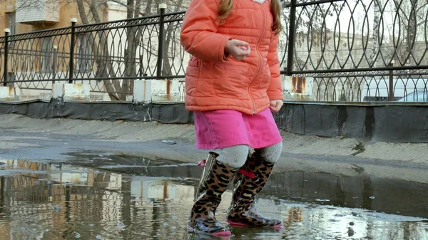 Lilla vackra flicka hoppa på vattenpölar efter regn — Stockfoto