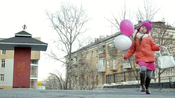 Niña hermosa saltando en charcos después de la lluvia con globos de colores — Foto de Stock