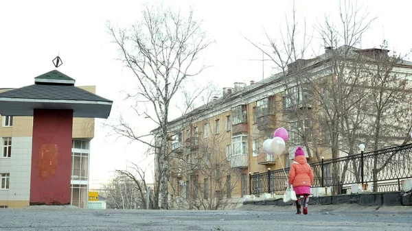 Kleines hübsches Mädchen springt nach Regen mit bunten Luftballons auf Pfützen — Stockfoto