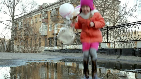 Lilla vackra flicka hoppa på vattenpölar efter regn — Stockfoto