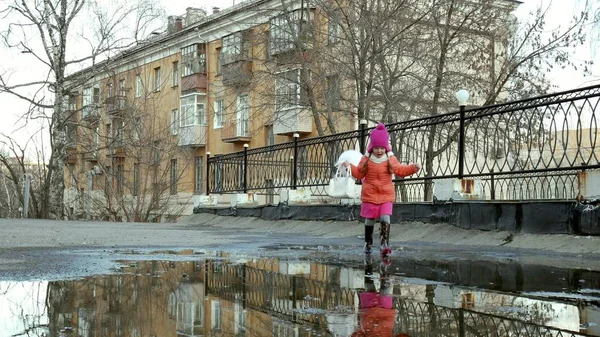 Pequena menina bonita pulando em poças após a chuva — Fotografia de Stock