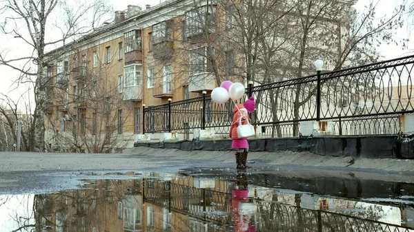 Маленькая красивая девочка прыгает на лужах после дождя — стоковое фото