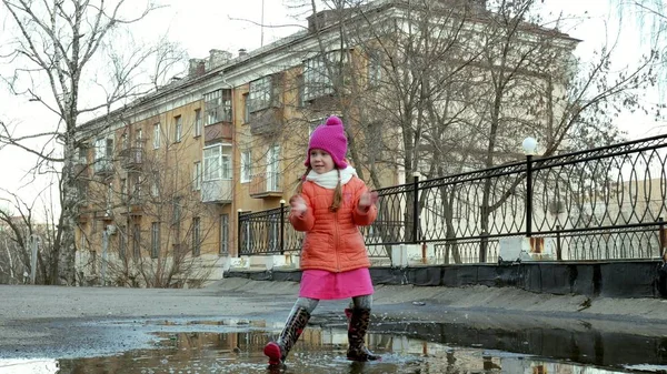 Little beautiful girl jumping on puddles after rain — Stock Photo, Image