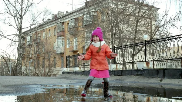 Pequena menina bonita pulando em poças após a chuva — Fotografia de Stock