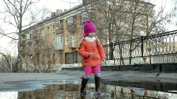 Lilla vackra flicka hoppa på vattenpölar efter regn — Stockfoto