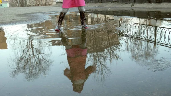 Lilla vackra flicka hoppa på vattenpölar efter regn — Stockfoto