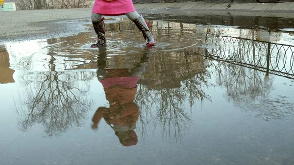 Pequena menina bonita pulando em poças após a chuva — Fotografia de Stock