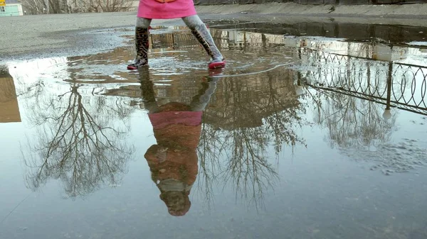 Lilla vackra flicka hoppa på vattenpölar efter regn — Stockfoto