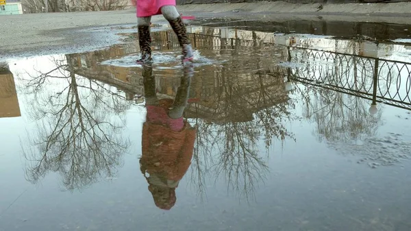 Küçük güzel kız su birikintileri üzerinde yağmur sonrası atlama — Stok fotoğraf