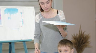 Çocuk erkek ve kız birlikte sınıf ve çizim masasının etrafında oturuyor. Onlarla birlikte onların genç ve güzel bir öğretmendir.