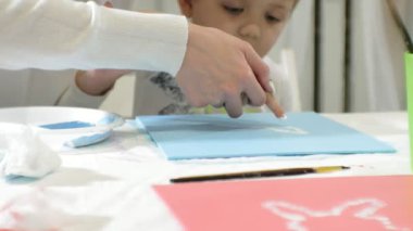 Çocuk erkek ve kız birlikte sınıf ve çizim masasının etrafında oturuyor. Onlarla birlikte onların genç ve güzel bir öğretmendir.