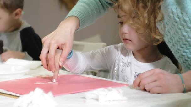 Kinderen-jongens en meisjes zitten samen rond de tafel in de klas en tekening. Met hen is hun jong en mooi leraar. — Stockvideo