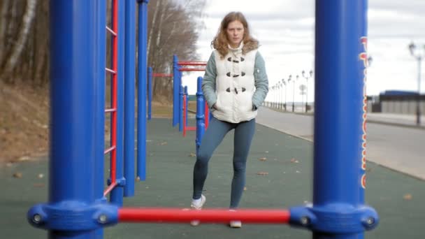 Unga fitness kvinna gör övningar på gymmet i en utomhus park — Stockvideo