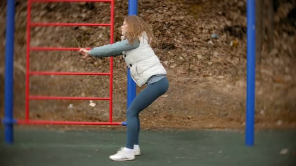 Unga fitness kvinna gör övningar på gymmet i en utomhus park — Stockvideo