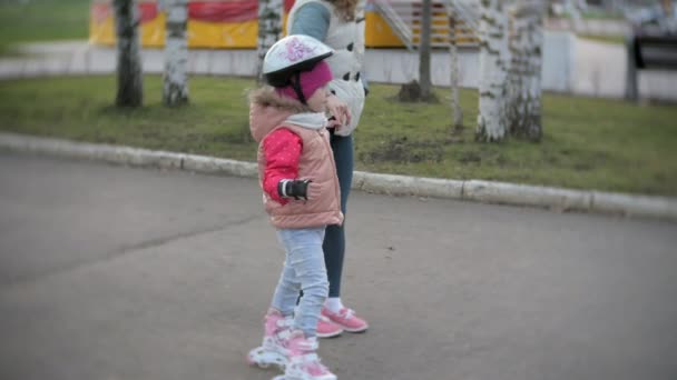 Maman et fille roulent en patins à roulettes. Une fille apprend à patiner et tombe. Maman enseigne fille à monter sur des rouleaux — Video