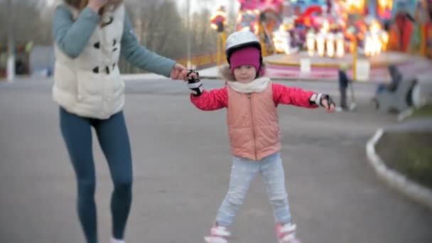 Mamá y su hija montan patines. Chica aprendiendo a patinar, y cae. Mamá enseña a su hija a montar en rodillos — Vídeo de stock