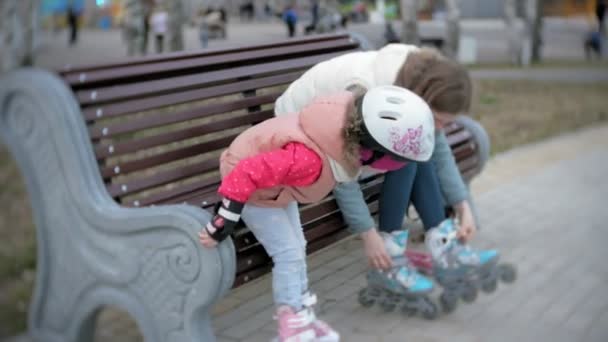 Mamá y su hija montan patines. Chica aprendiendo a patinar, y cae. Mamá enseña a su hija a montar en rodillos — Vídeo de stock