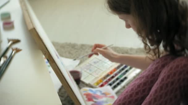 Ung kvinna målning konstnär hemma sitter på det våningen kreativt måleriet — Stockvideo