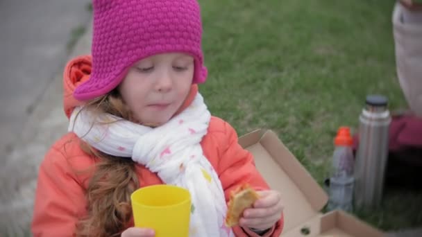 Egy szép kis lány és az anyja enni pizzát a szabadban. Táplálkozás-, élelmiszer- és életmód — Stock videók