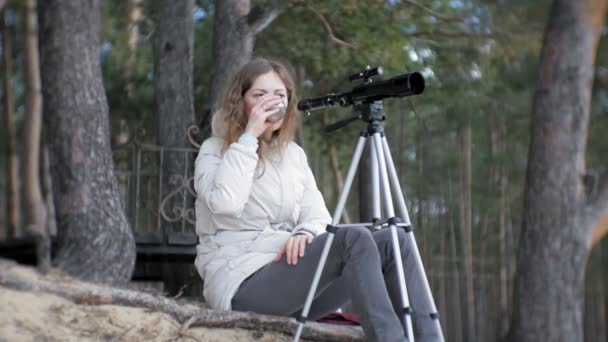 Mujer atractiva mira a través de un telescopio en un bosque en la orilla del río — Vídeos de Stock