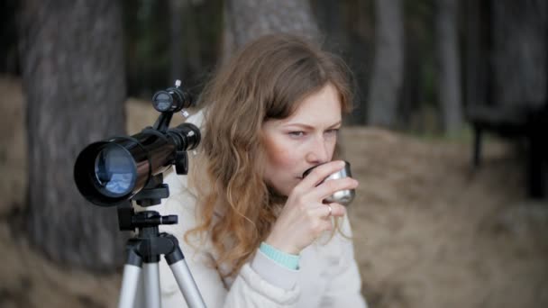 Donna attraente guarda attraverso un telescopio in una foresta sulla riva del fiume — Video Stock