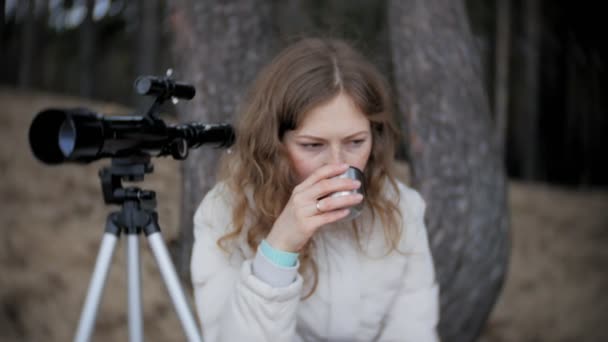 Femme attirante regarde à travers un télescope dans une forêt sur la rive de la rivière — Video