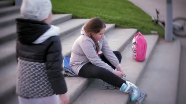 Маленькая девочка одевает ролики на коньках. Концепция: спорт, образ жизни, здоровье . — стоковое видео