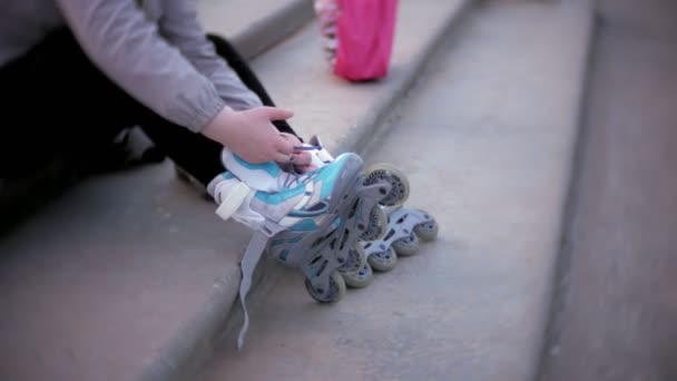 Маленька дівчинка одягається кататися на роликах. Концепція: спорт, спосіб життя, здоров'я . — стокове відео