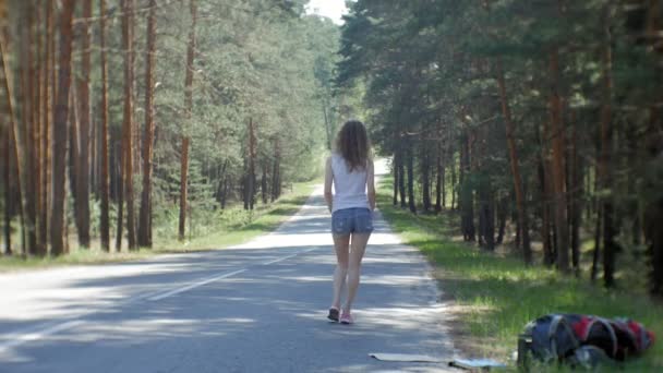 Joven hermosa mujer autostop de pie en la carretera con una mochila en una mesa con una inscripción SUR — Vídeo de stock