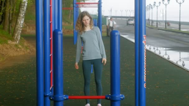 Молодая фитнес-женщина делает упражнения на тренажерном зале в открытом парке — стоковое видео