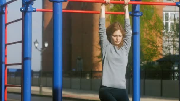 Junge Fitness-Frau macht Übungen auf der Turnhalle in einem Outdoor-Park — Stockvideo