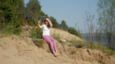 Bir ormanda bir akıllı telefon kullanan genç kadın. Güzel kız ormanda telefonda yazarak.