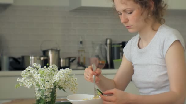 一个美丽的年轻女人吃鸡肉意大利面食在家庭厨房 — 图库视频影像