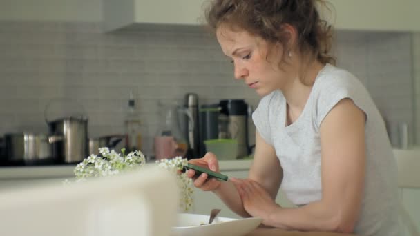 一个美丽的年轻女人吃鸡肉意大利面食在家庭厨房 — 图库视频影像